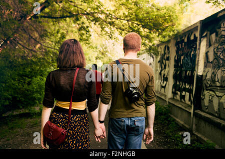 Caucasian couple holding hands in urban park Stock Photo