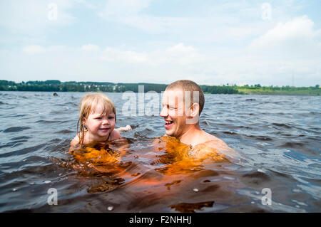 Caucasian father and daughter swimming in lake