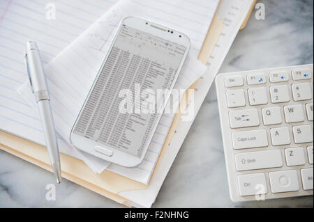 Close up of computer keyboard, files and cell phone on office desk Stock Photo