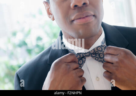 Groom in tuxedo adjusting bow tie