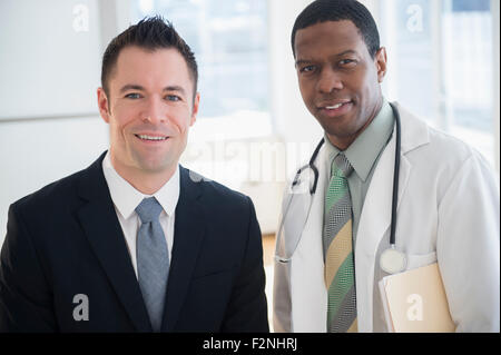 Businessman and doctor smiling in office Stock Photo