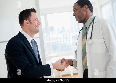 Businessman and doctor shaking hands in office Stock Photo