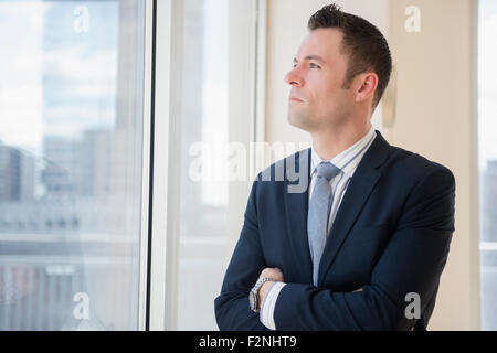 Businessman looking out office window Stock Photo