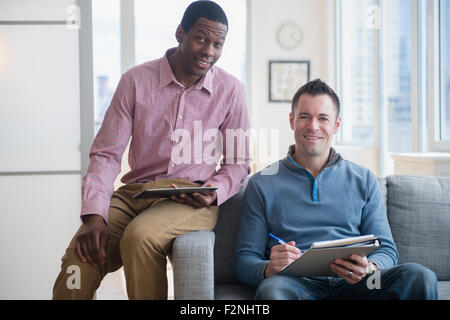 Businessmen with digital tablet and notepad on sofa Stock Photo