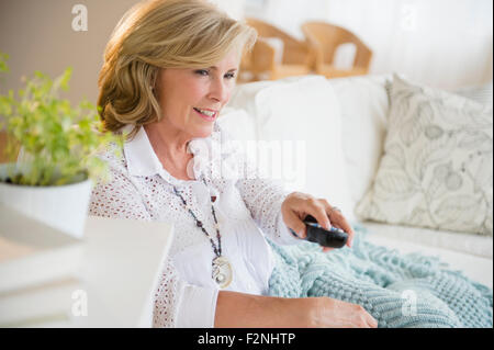 Caucasian woman watching television on sofa Stock Photo