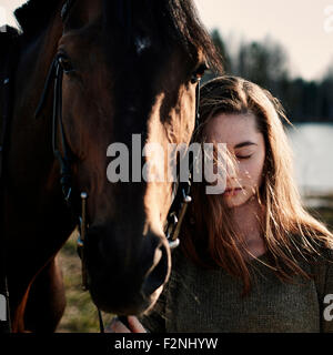 Caucasian woman walking with horse in field Stock Photo