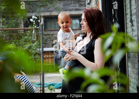 Woman holding baby son in backyard Stock Photo
