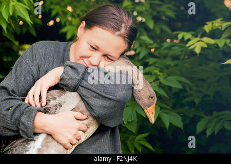 Caucasian farmer hugging goose in garden Stock Photo