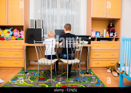 Caucasian brothers using computer in bedroom Stock Photo