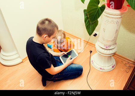 Caucasian brothers using digital tablet on floor Stock Photo