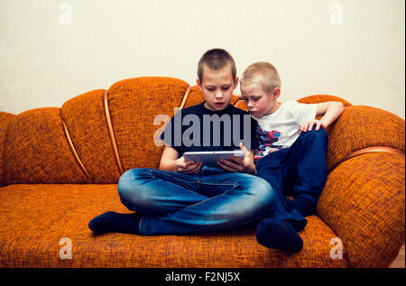 Caucasian brothers using digital tablet on sofa Stock Photo