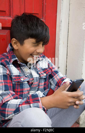 Asian boy using cell phone at door Stock Photo