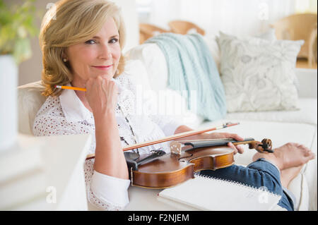 Caucasian woman holding violin on sofa Stock Photo