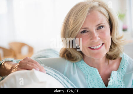 Caucasian woman smiling on sofa Stock Photo