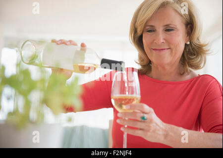 Caucasian woman pouring glass of white wine Stock Photo