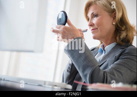Caucasian businesswoman applying makeup in office Stock Photo