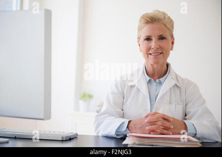 Caucasian doctor sitting at office desk Stock Photo