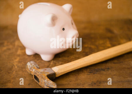 Close up of piggy bank and hammer on table Stock Photo