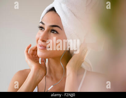 Woman with hair in towel listening to headphones Stock Photo
