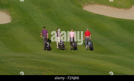 Caucasian friends pulling golf bags on course Stock Photo