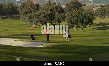 Caucasian couple playing golf on course Stock Photo