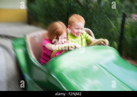 Caucasian children on ride in amusement park Stock Photo