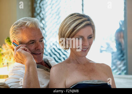 Caucasian couple talking on cell phone in hotel lobby Stock Photo
