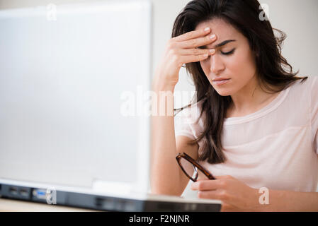 Stressed woman rubbing her forehead at laptop Stock Photo
