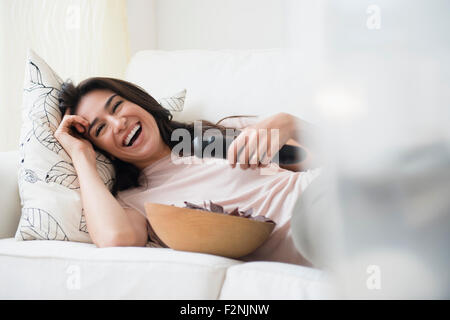 Woman watching television on sofa Stock Photo
