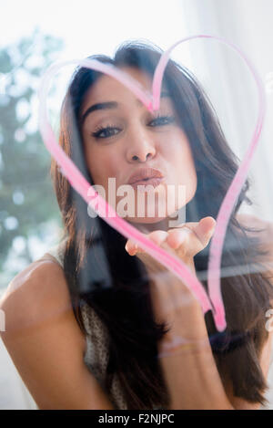 Close up of woman blowing a kiss through heart Stock Photo