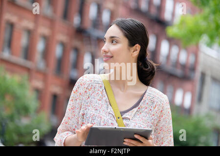 Hispanic woman using digital tablet in city Stock Photo