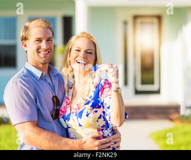 Caucasian couple holding keys outside new home Stock Photo