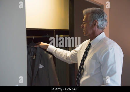 Caucasian businessman selecting suit from closet Stock Photo