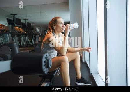 Woman drinking water bottle in gym Stock Photo
