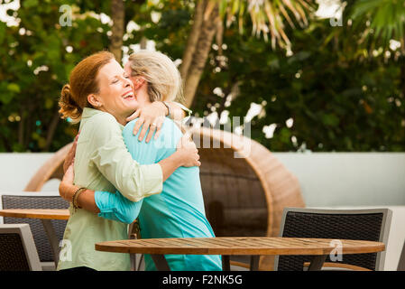 Caucasian women hugging on restaurant patio Stock Photo