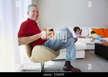 Grandfather and grandchildren relaxing in living room Stock Photo