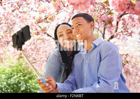 Friends taking self portrait under flowering tree Stock Photo