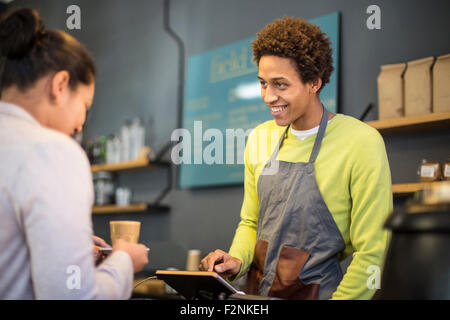 Mixed race barista assisting customer in coffee shop Stock Photo