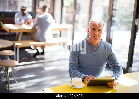 Older man using digital tablet in cafe Stock Photo