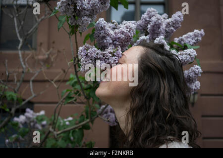 Caucasian woman smelling flowers on city street Stock Photo