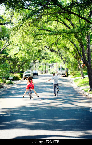 Caucasian children riding bicycles on suburban neighborhood street Stock Photo