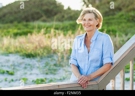 Smiling Caucasian woman standing on beach Stock Photo