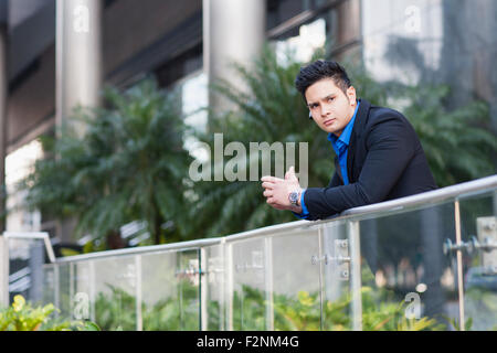 Mixed race businessman leaning on banister Stock Photo