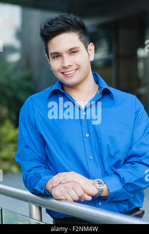 Mixed race businessman leaning on banister outdoors Stock Photo