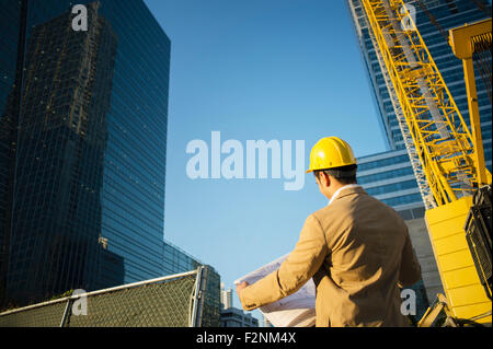 Mixed race architect reading blueprints at construction site Stock Photo