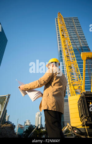 Mixed race architect reading blueprints at construction site Stock Photo