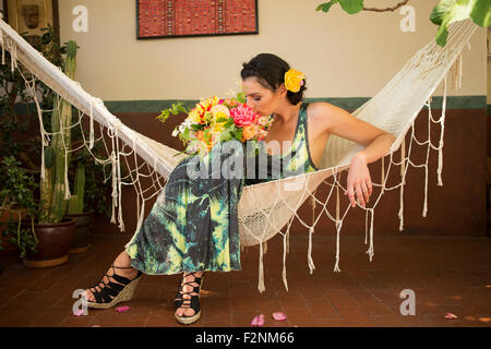 Woman smelling bouquet of flowers in hammock Stock Photo
