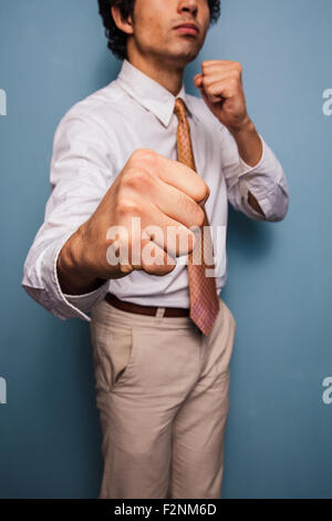 Young man standing by a blue wall throwing punches Stock Photo