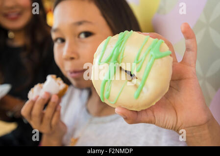Close up of girl holding donut in bakery Stock Photo