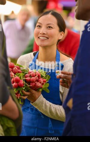 Clerk holding produce at farmers market Stock Photo